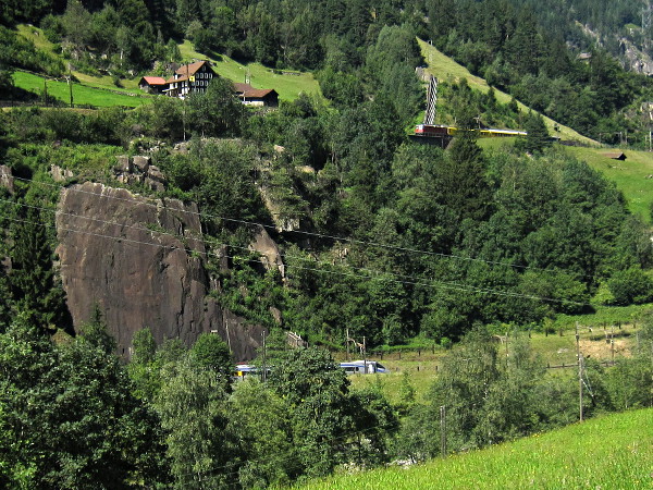 [Tunnel elicoidale di Pfaffensprung, presso Gurtnellen.  Sono
visibili i due livelli della ferrovia: su quello superiore transita un
convoglio diagnostico trainato da una Re 4/4.  Su quello inferiore un
elettrotreno ETR 470.]