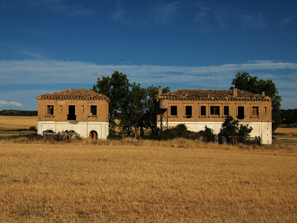 [I due edifici gemelli della stazione di Turuñana.  Nella foto si vede
la  facciata dal  lato  opposto al  binario.   Loscorrales, 11  agosto
2019.]