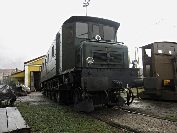 [Vista di 3/4
della locomotiva elettrica SBB Ae 4/7 10987 a Luino.  Visibili l'asse
portante e le scatole degli ingranaggi della trasmissione Buchli sui
quattro assi motori]